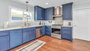 Una cocina moderna con armarios azules, electrodomésticos de acero inoxidable y un ventanal grande.