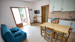 A compact living space with a dining area, a sofa, a TV, and a kitchen. - ALLOGGI DEL MIRTO - BILLY DEL MIRTO (Capoliveri)