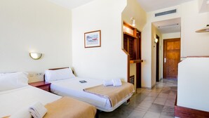 A hotel room with two beds, a wooden nightstand, a framed picture on the wall, and a door leading to another room.