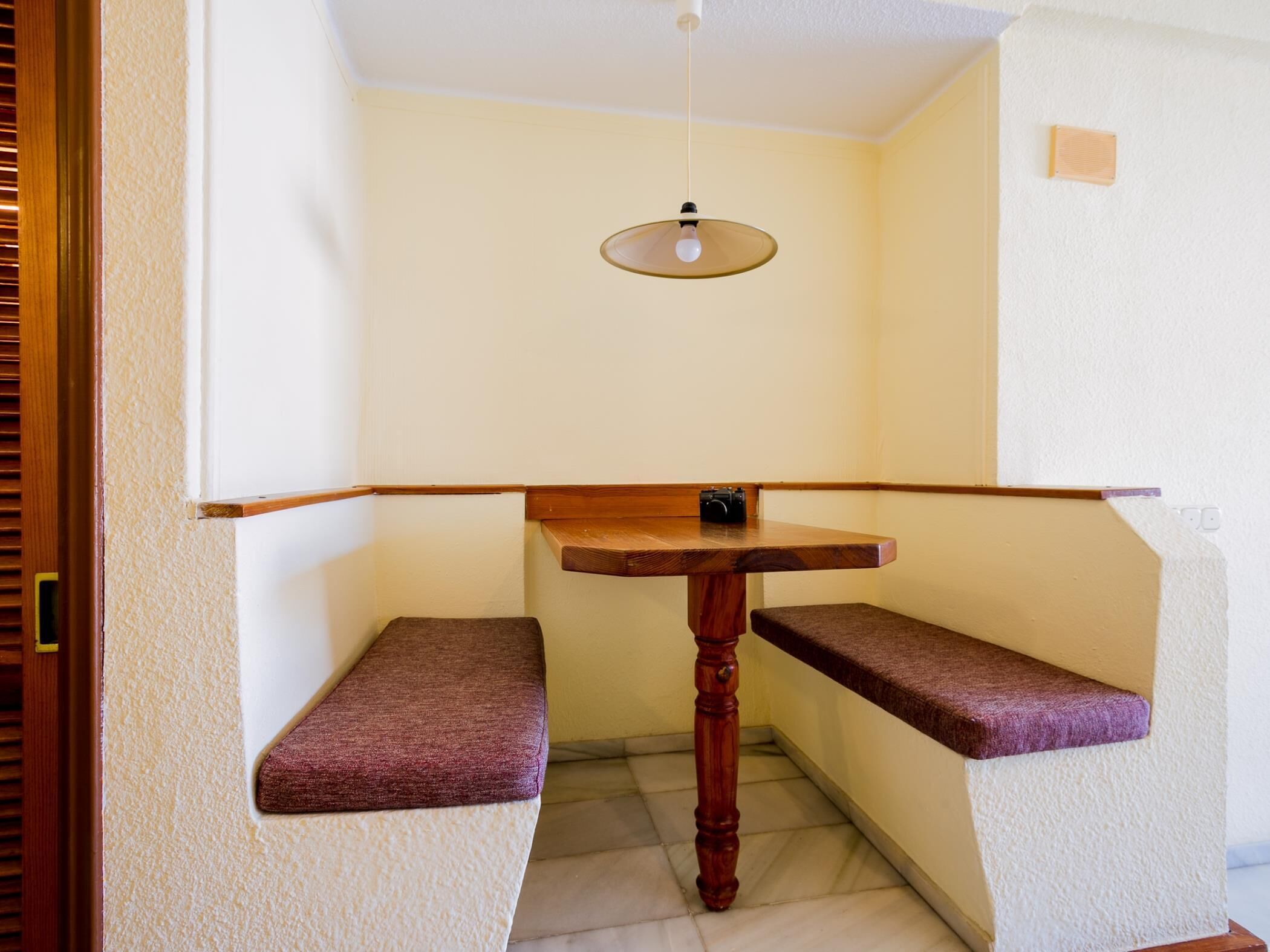 Ein Eckzimmer mit einem Holztisch und zwei gepolsterten Bänken.