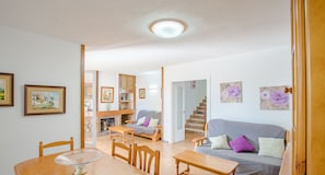 Ein Wohnzimmer mit Esstisch, Stühlen, einer Couch und einer Treppe zu einem anderen Raum.