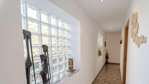 Ein Korridor mit einem großen Fenster, einem Marmorboden und einer Wand mit dekorativen Elementen.
