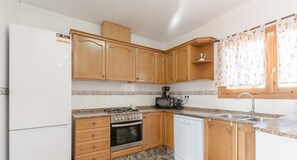 A kitchen with wooden cabinets, a stove, oven, dishwasher, and a microwave.