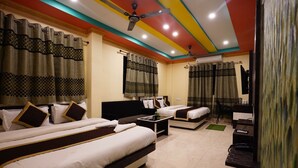 A hotel room with two beds, a desk, and a ceiling fan. - Tirupati Lodge Private Limited (Jalpaiguri)