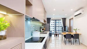 A modern kitchen with a built-in stove, a dining area with a table and chairs, and a large window offering a view of the city.