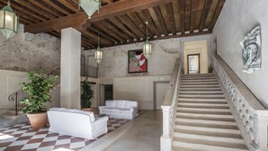 Un'ampia hall con pavimento a scacchi, divani bianchi, una scala e lanterne sospese.