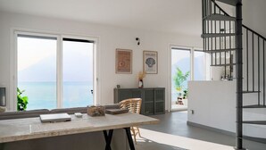 Een modern interieur met een eethoek, een trap en uitzicht op zee.