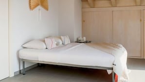 Een slaapkamer met een bed, een plafondventilator en houten balken.