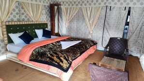 Una habitación con una cama, una silla y una mesita.