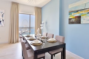 Enjoy meals in this dining area with a long table and comfortable chairs, offering a view of a nearby Ferris wheel.