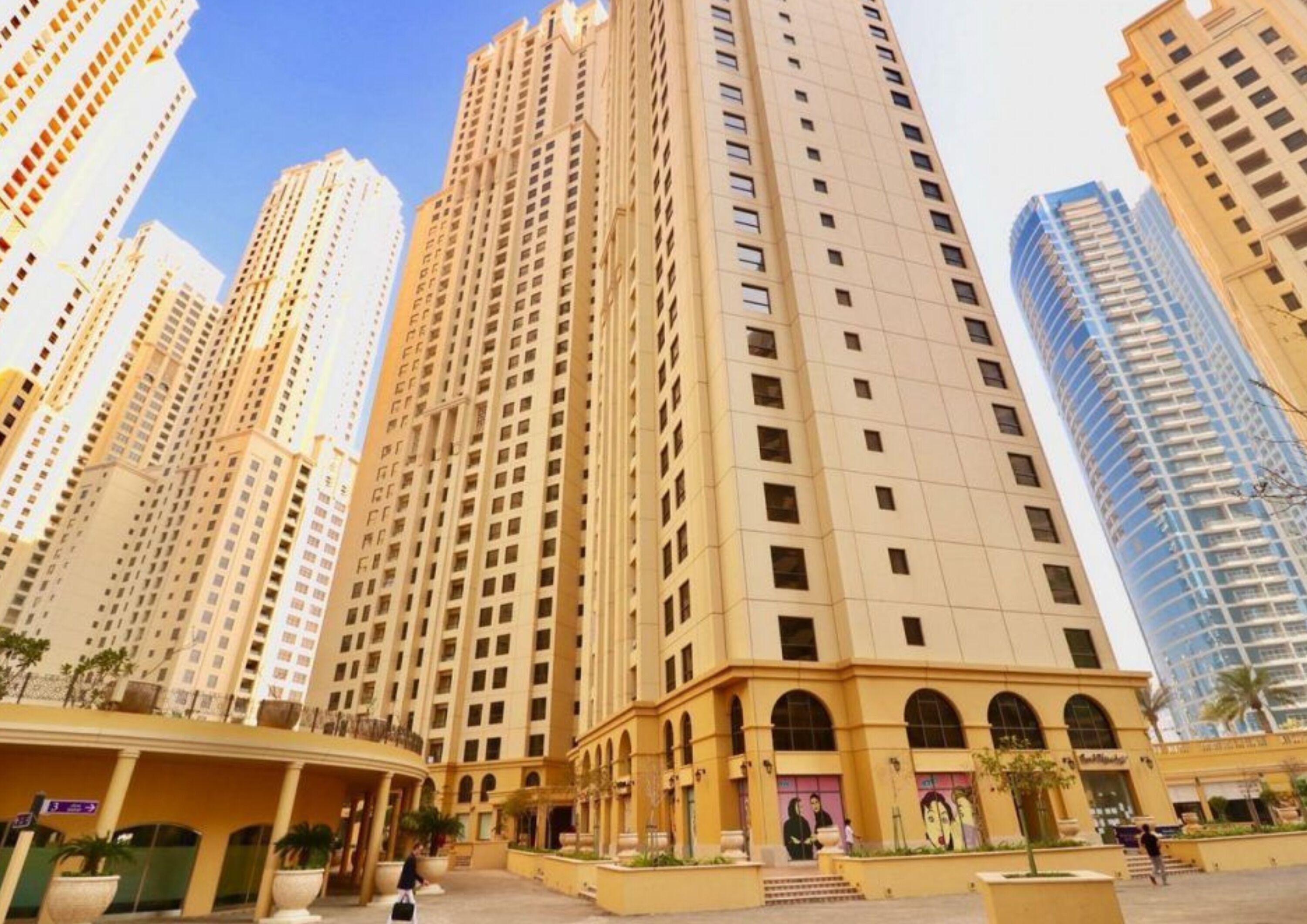 A high-rise residential building with multiple balconies and a central courtyard with steps leading to an entrance.