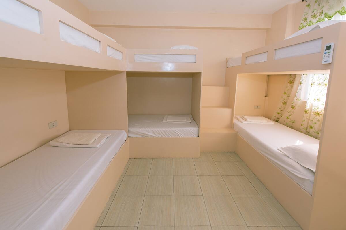 Ein Zimmer mit Etagenbetten, einem kleinen Fenster und einer Bedienkonsole an der Wand.
