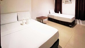 A hotel room with two beds, a small table, and a wall-mounted air conditioner. - FB Budgetel Suites (Cagayan de Oro)