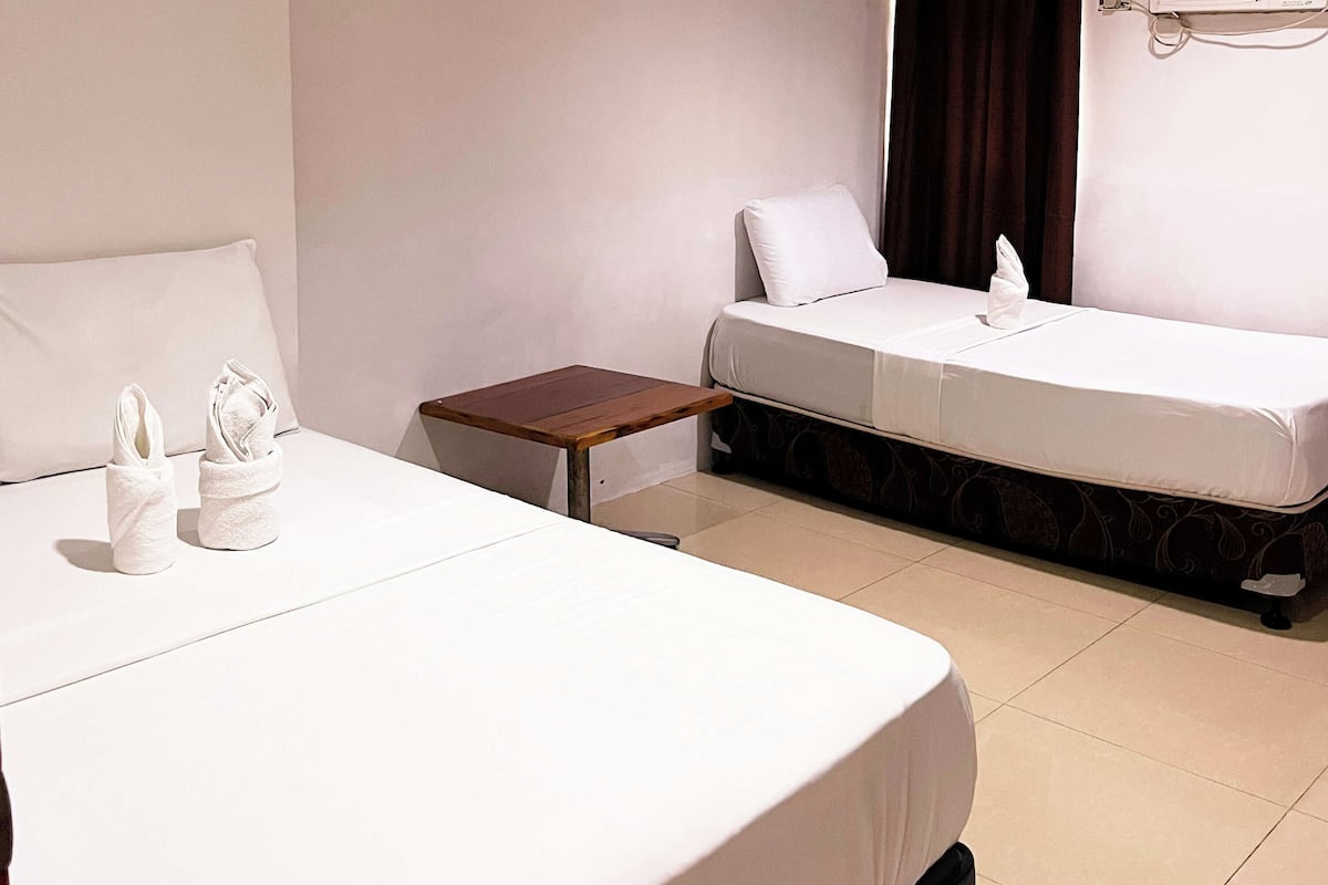 Ein Hotelzimmer mit zwei Betten, einem kleinen Holztisch und einer weißen Wand.
