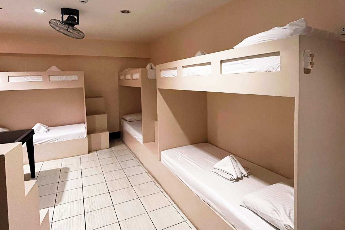 Ein Zimmer mit Etagenbetten, einem Ventilator und einem gefliesten Boden.