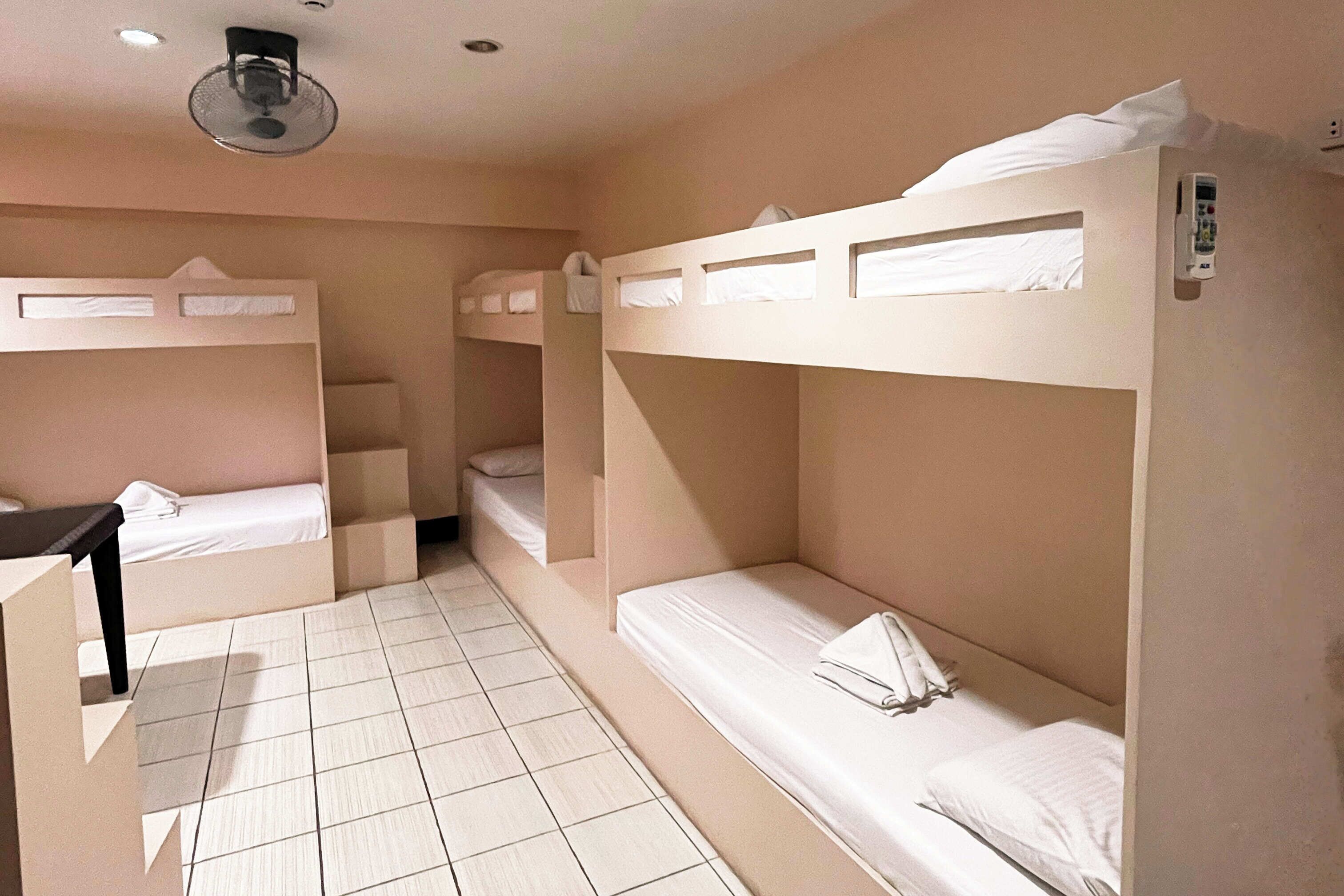 Ein Zimmer mit Etagenbetten, einem Schreibtisch und einem Deckenventilator.