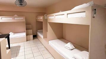 Ein Zimmer mit Etagenbetten, einem Schreibtisch und einem Deckenventilator.