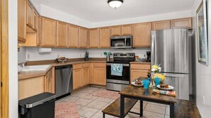 A modern kitchen with wooden cabinets, stainless steel appliances, and a dining area with a table and chairs.