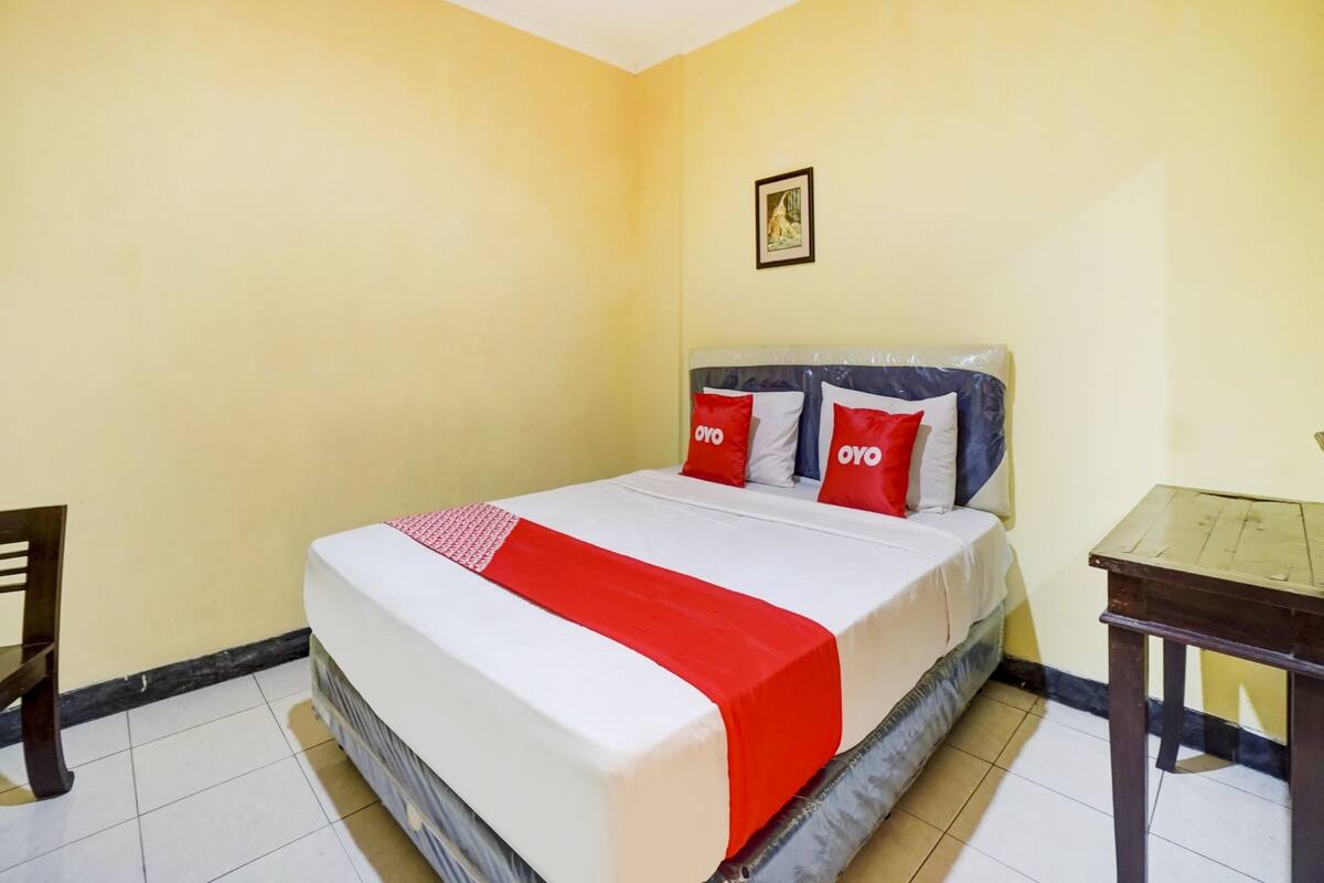 Een hotelkamer met een bed, een tafeltje en een stoel.