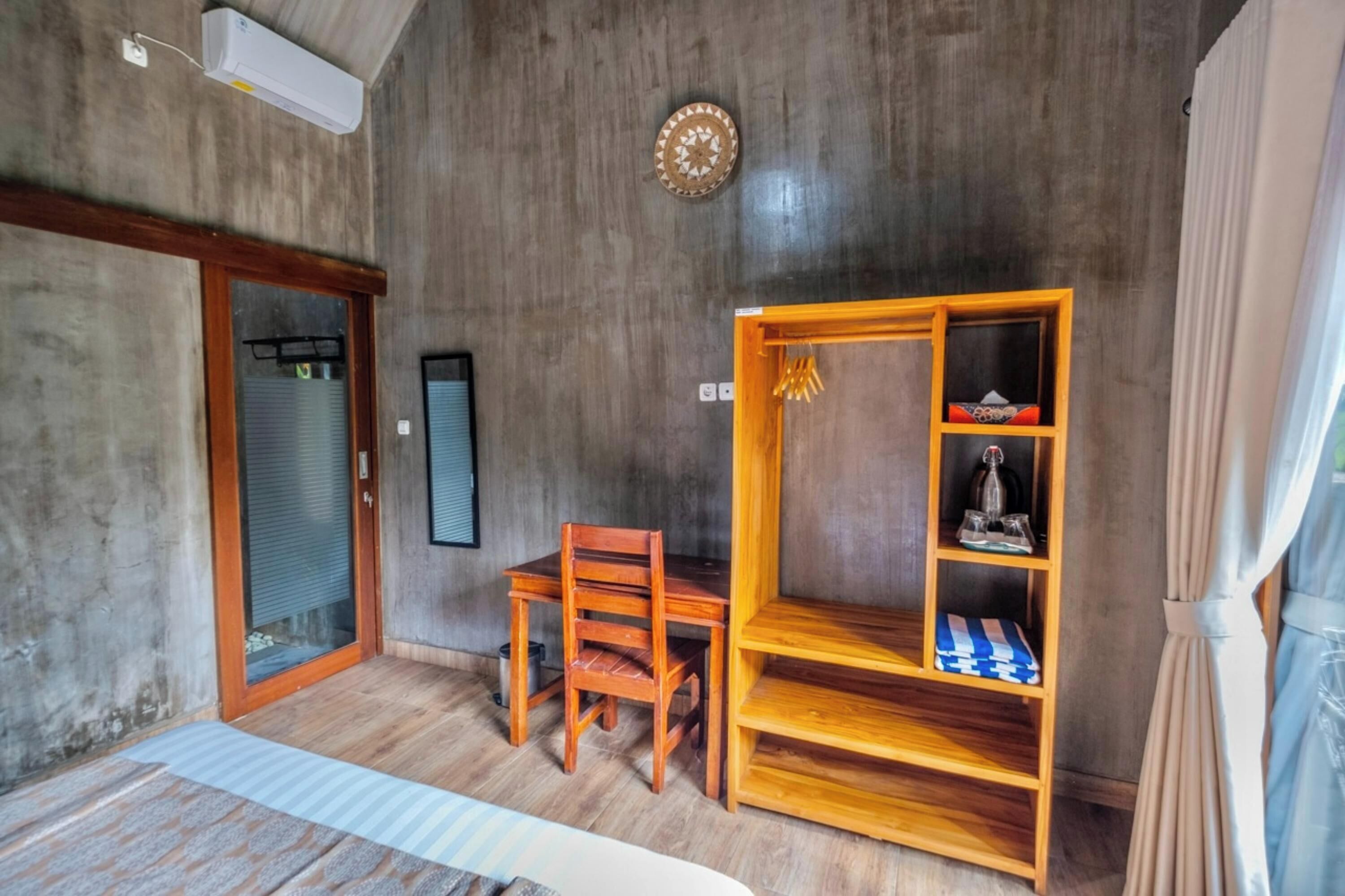 A room with a wooden desk, a chair, a shelf with decorative items, a clock on the wall, and a sliding door.
