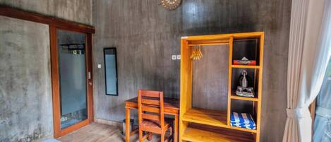 A room with a wooden desk, a chair, a shelf with decorative items, a clock on the wall, and a sliding door.