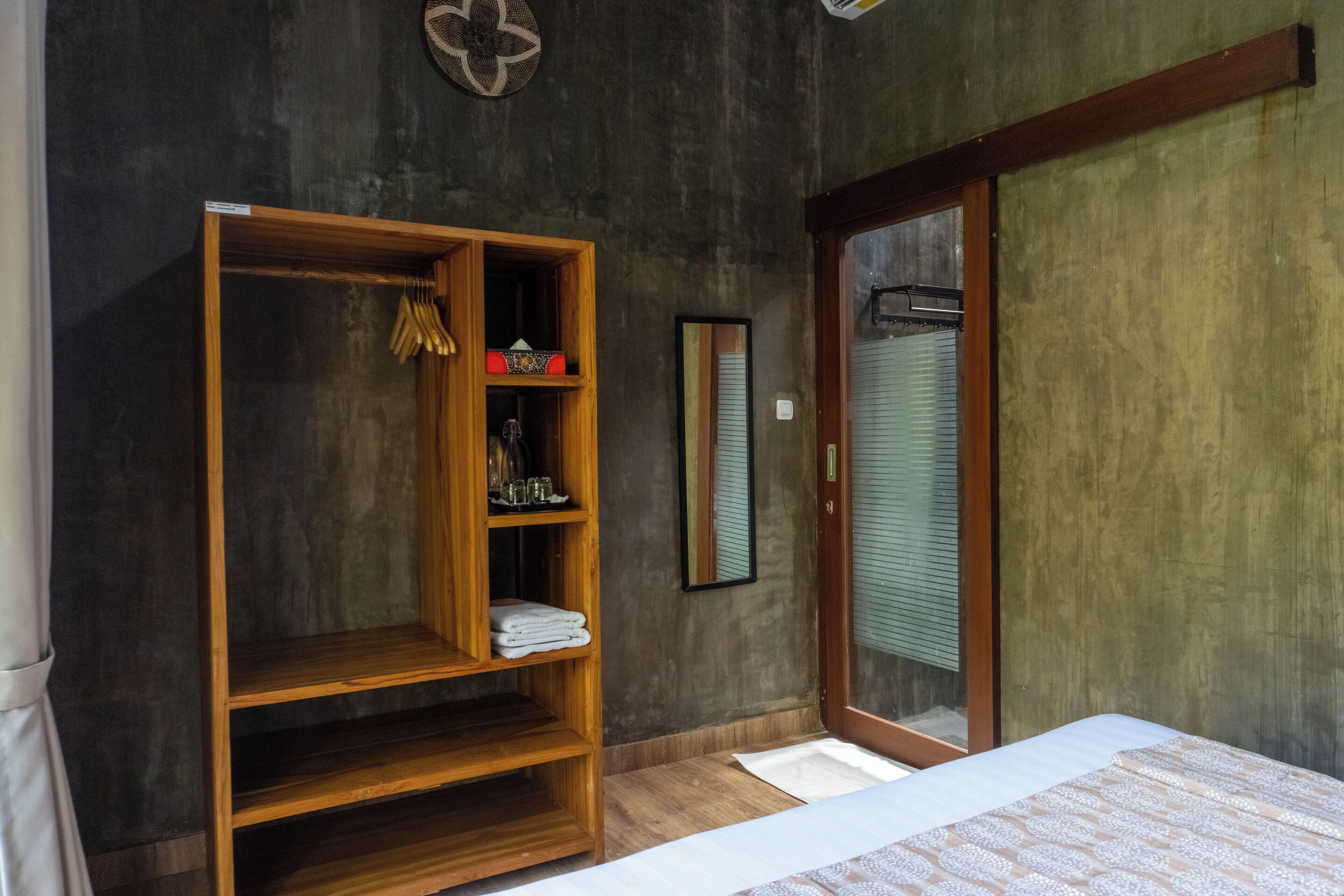 A bedroom with a wooden wardrobe, a bed with a patterned bedspread, and a sliding glass door.