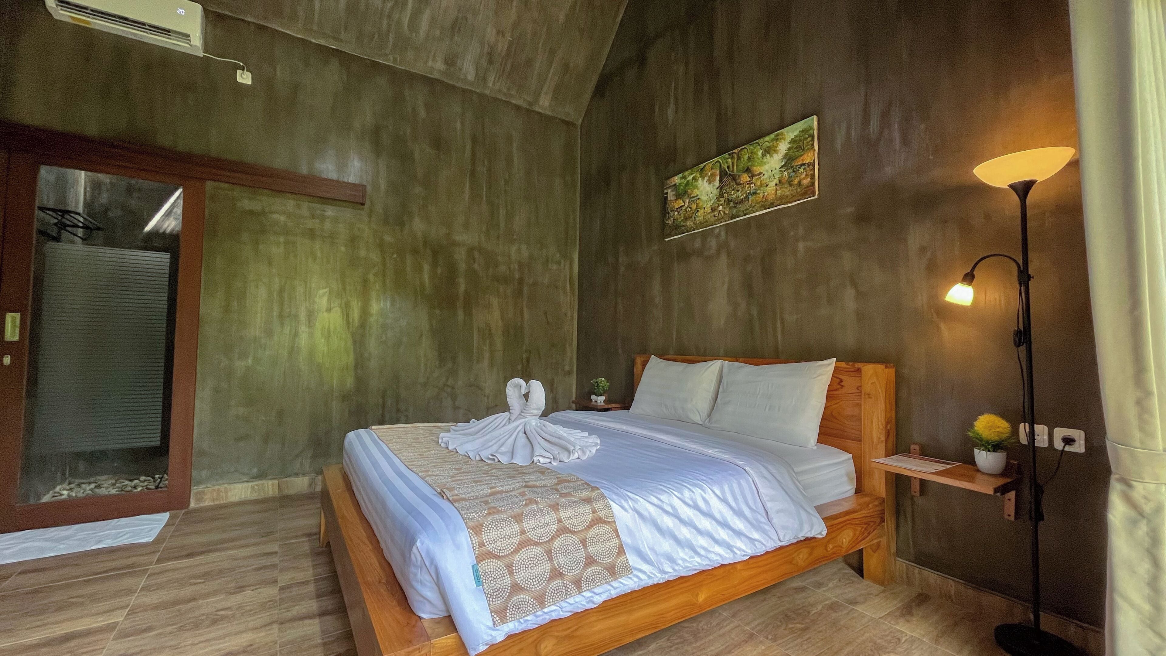 Une chambre à coucher avec un lit en bois, une table de chevet avec une lampe, un tableau au mur et une grande fenêtre donnant sur un beau paysage.