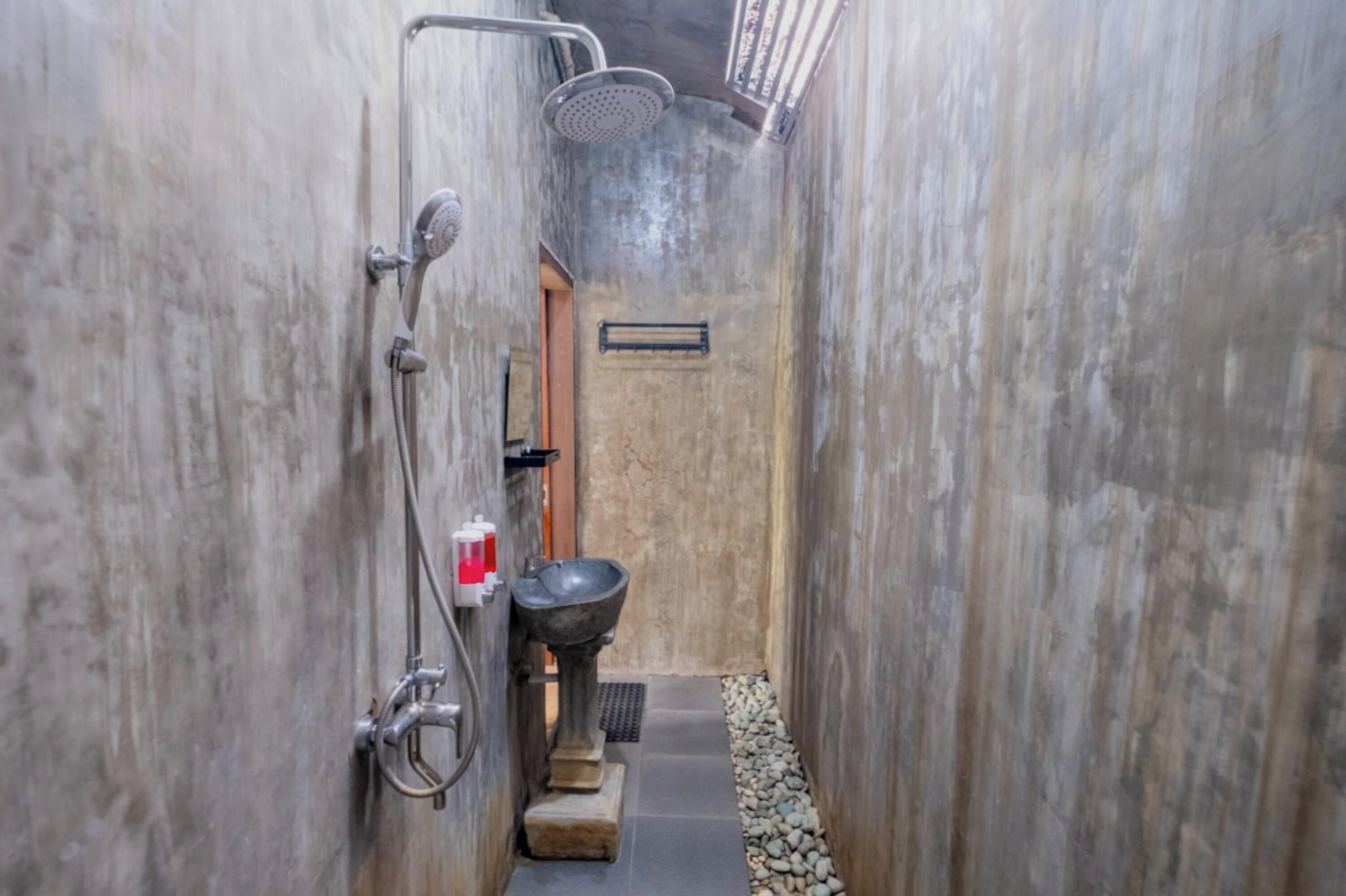 Ein schmales Badezimmer mit Dusche, Waschbecken und Toilette.