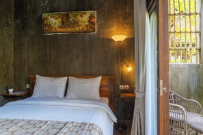 A bedroom with a bed, a nightstand, a lamp, and a painting on the wall. - Elemento Homestay Badung (Abiansemal)