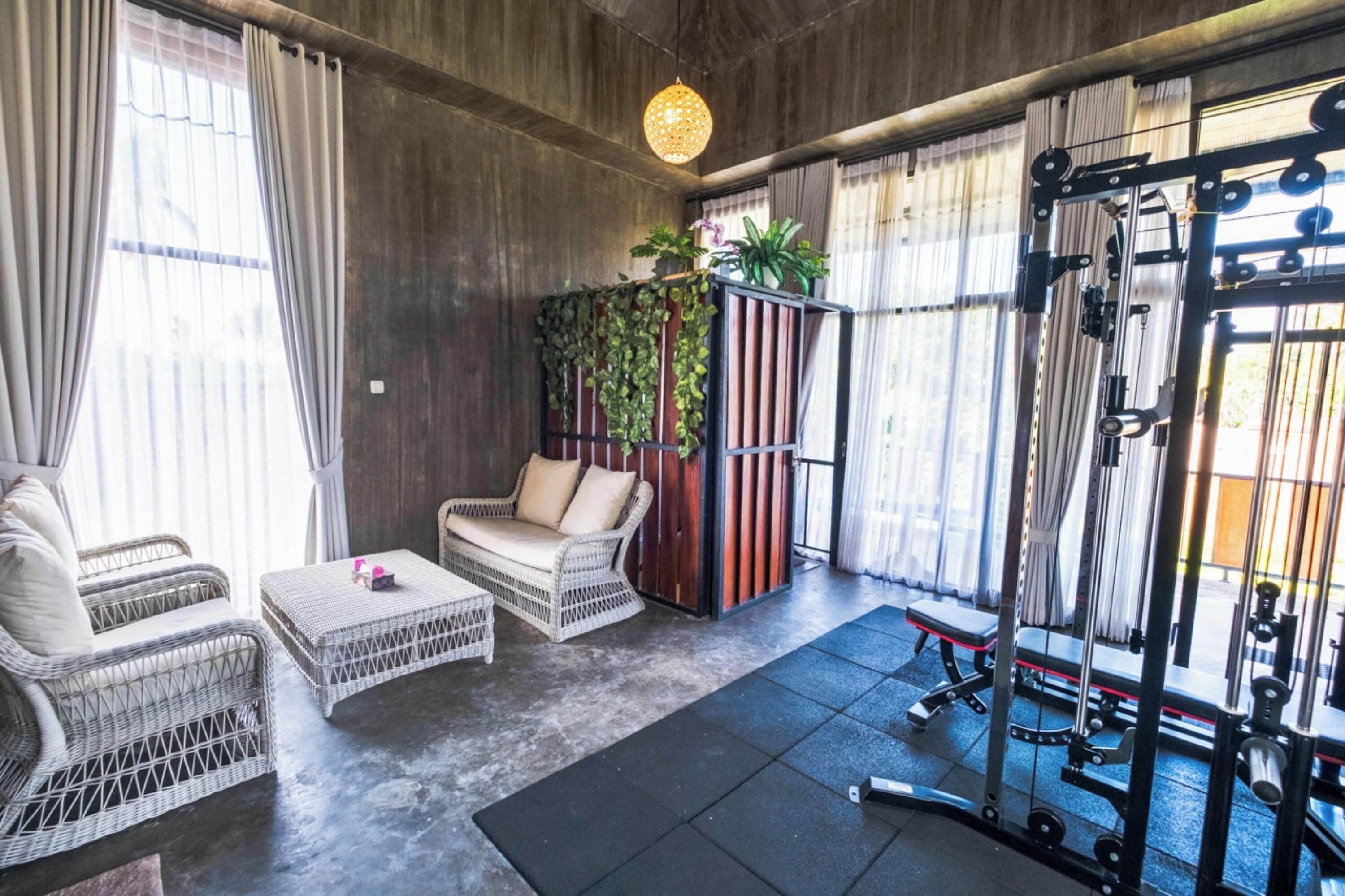 A gym with exercise equipment, wicker furniture, and a plant wall.