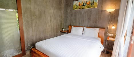 Um quarto com cama de madeira, mesa de cabeceira, pintura na parede e luminária de chão.
