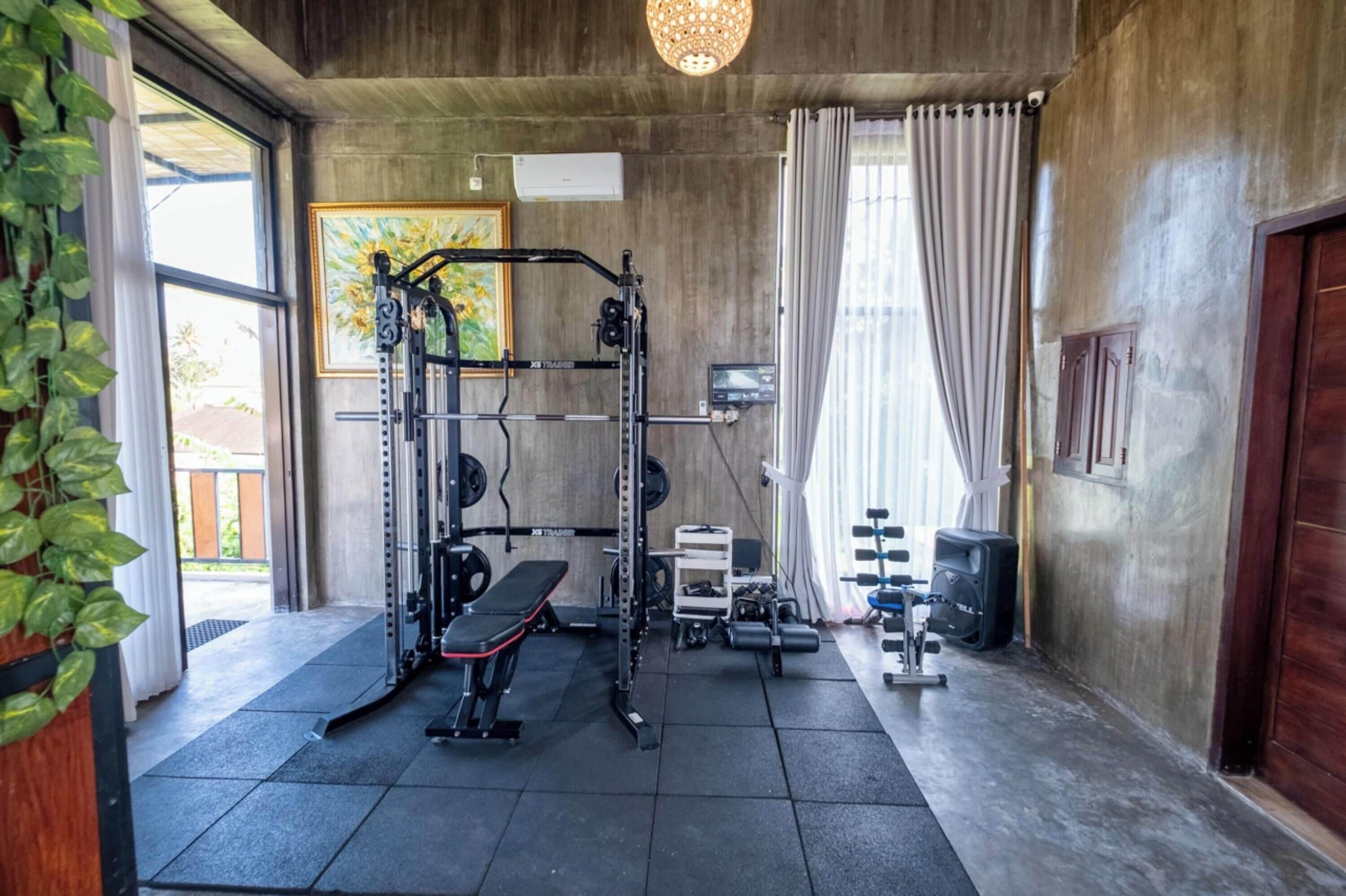 Un gimnasio con una estructura para sentadillas, banco y pesas.
