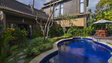 Una propiedad residencial con piscina, rodeada de vegetación exuberante y tejado de baldosas.