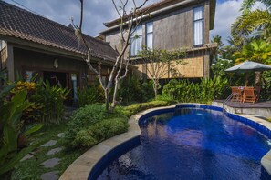 A residential property with a swimming pool, surrounded by lush greenery and a tiled roof. - Elemento Homestay Badung (Abiansemal)