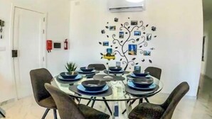 Un espace repas avec une table ronde, des chaises noires et des luminaires suspendus.