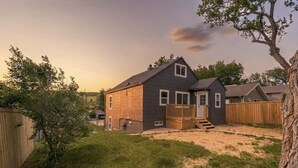 A two-story house with a wooden deck, a front door, and a visible garage. - 821 N7th Upstairs · Trendy Stay2- 3 bed1 bath, Close to Monument Arena (Rapid City)