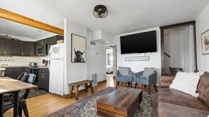 A modern living room with a wooden coffee table, a sofa, and a TV mounted on the wall. - 821 N7th Upstairs · Trendy Stay2- 3 bed1 bath, Close to Monument Arena (Rapid City)