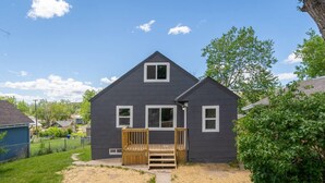 A two-story house with a front porch and a small deck. - 821 N7th Upstairs · Trendy Stay2- 3 bed1 bath, Close to Monument Arena (Rapid City)
