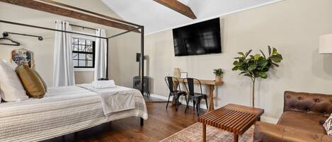 Un dormitorio con cama, escritorio, silla, televisor y planta.