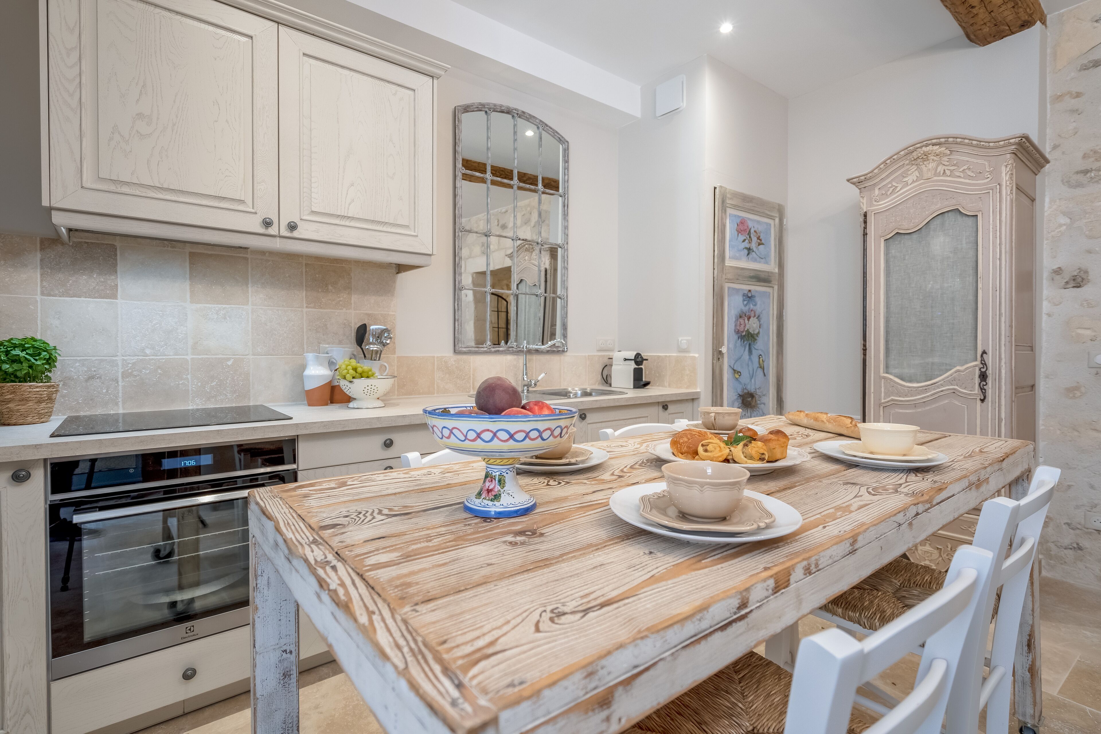 A kitchen with a wooden table, white chairs, and a built-in oven.