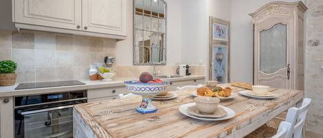 A kitchen with a wooden table, white chairs, and a built-in oven.