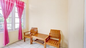Une pièce d’angle avec une table en bois et deux chaises, des rideaux roses et une fenêtre donnant sur l’extérieur.