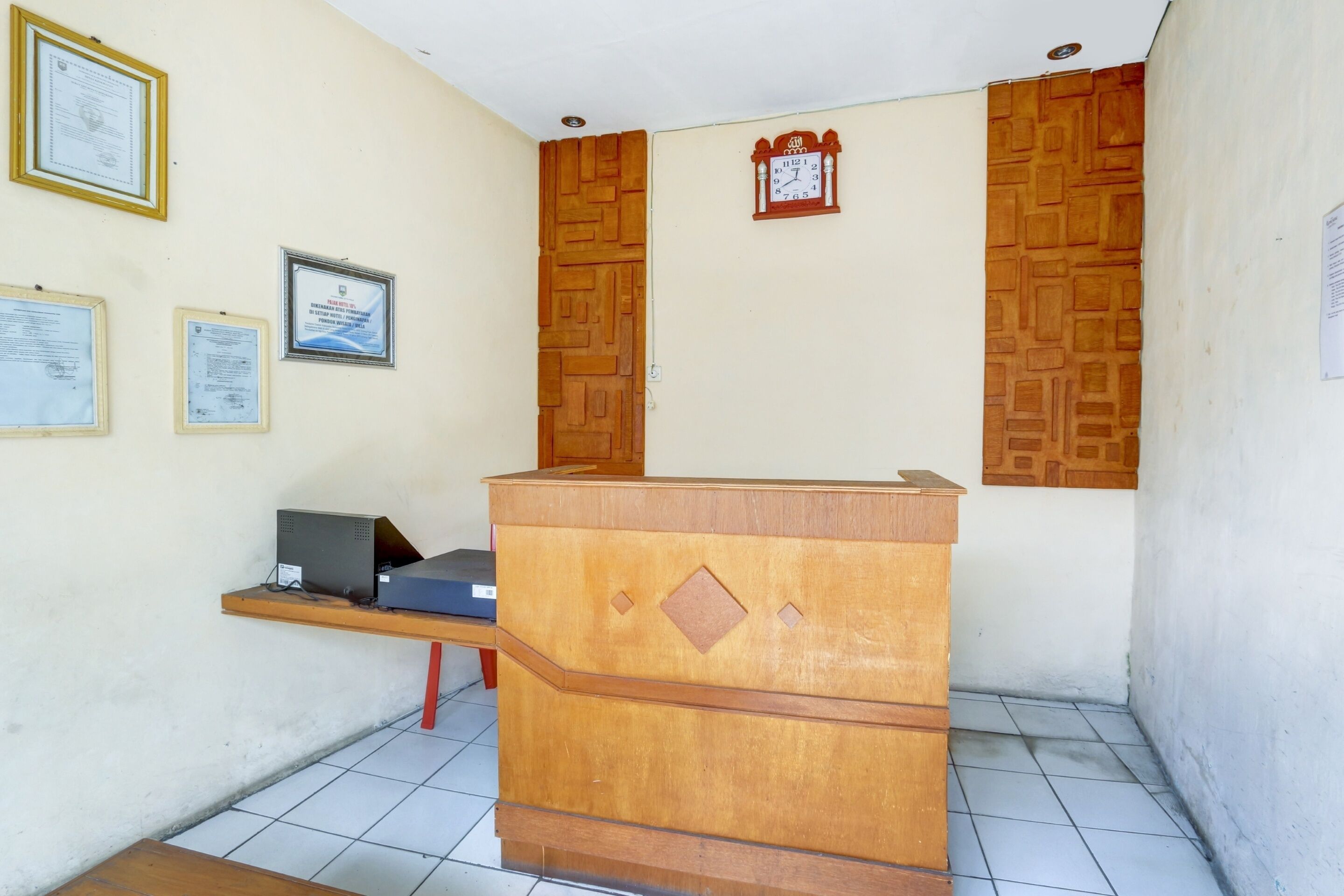 A reception desk with certificates on the wall, a clock, and a patterned wall.