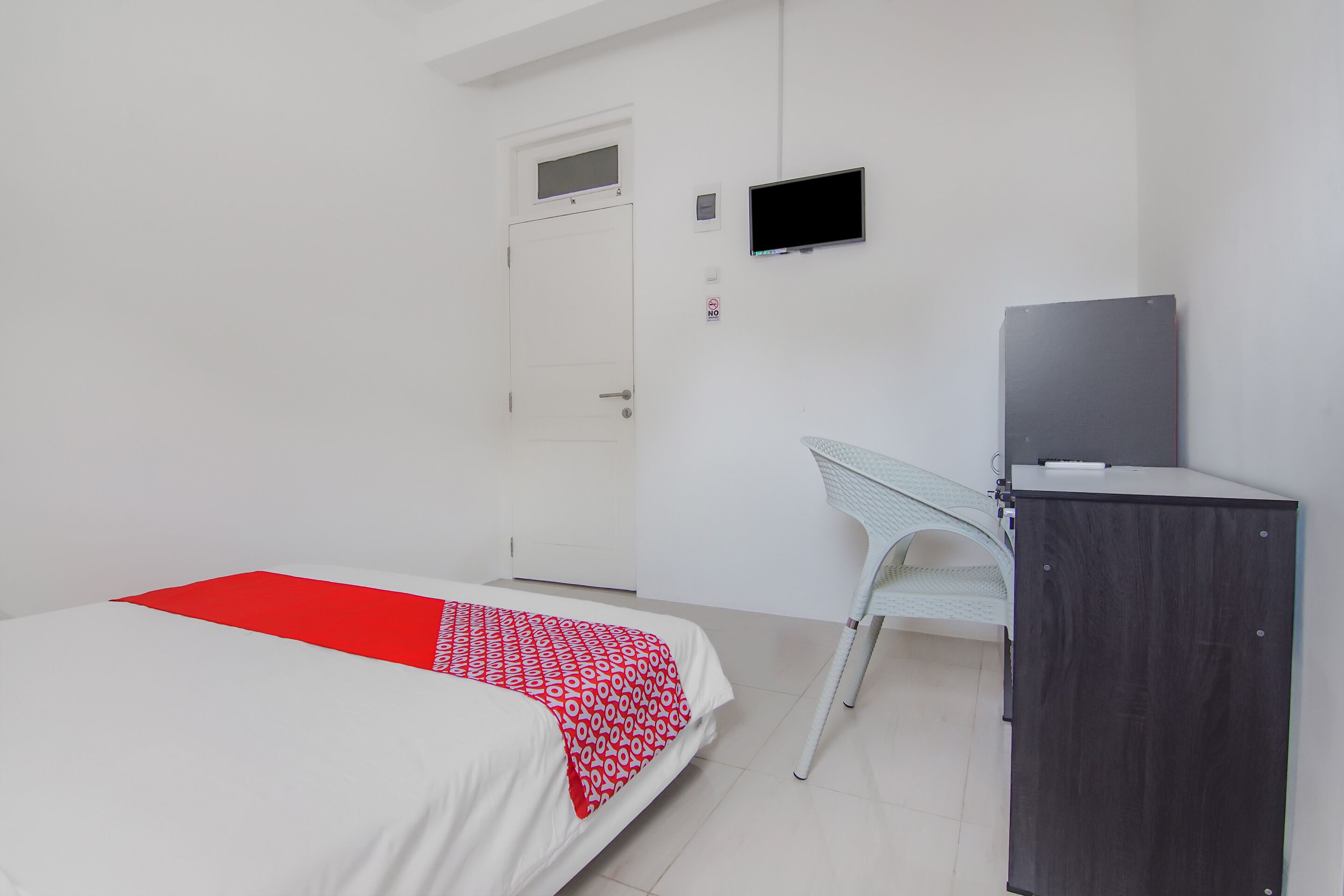 Ein Zimmer mit einem Bett, einem Schreibtisch, einem Stuhl, einem Fernseher und einer Tür.