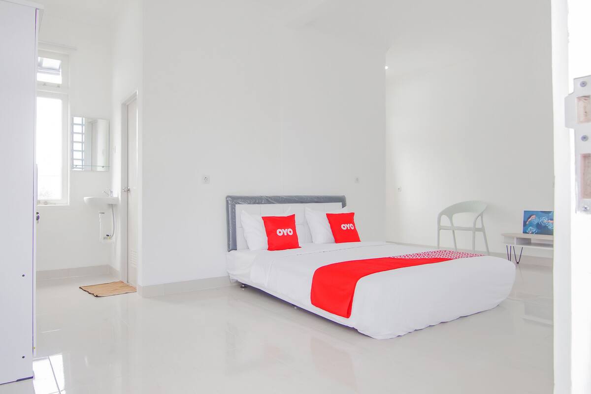 A modern bedroom with a bed, a chair, and a desk.