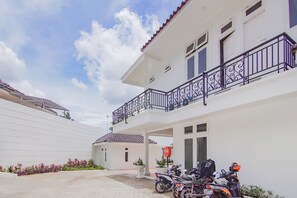 A two-story building with a balcony, a covered parking area, and a stop sign. - Capital O 90342 Kemang Garden (Jakarta)