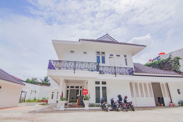A two-story building with a balcony, a sign reading "OYO," and several parked scooters in front. - Capital O 90342 Kemang Garden (Jakarta)
