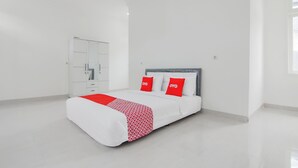A modern bedroom with a bed, white wardrobe, and a window. - Capital O 90342 Kemang Garden (Jakarta)