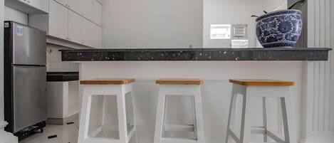 A kitchen with white cabinets, a black countertop, and two wooden stools.