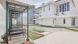 A residential building with a covered outdoor seating area, a small garden, and a tiled pool. - Capital O 90342 Kemang Garden (Jakarta)